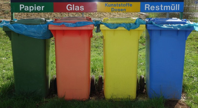 Four Colorful recycling bins for paper, glass, plastic jars, and mixed waste. Clear instructions and well-planned solutions would make recycling more appealing for citizens.
